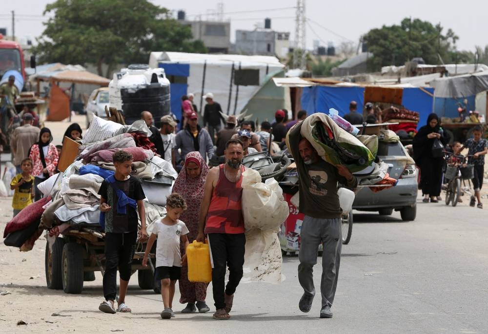 Palestinians travel on foot along with their belongings as they flee Rafah due to an Israeli military operation, in Rafah, on Tuesday. REUTERS