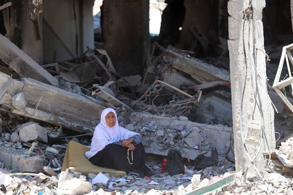A Palestinian woman sits amid the rubble of a building in the Jabalia refugee camp in the northern Gaza Strip, as she returned briefly with people who sought to check on their homes on Friday. AFP