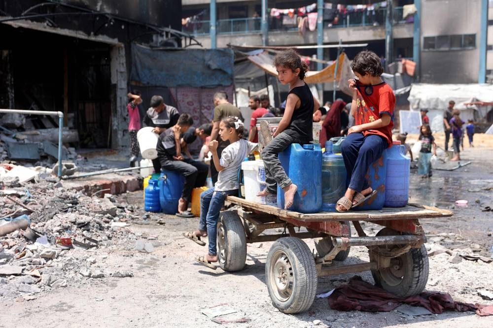 Palestinian children sit on a cart laden with containers as they wait to fill them with water a partially destroyed school being used as a shelter in the Jabalia refugee camp, in the northern Gaza Strip on Monday. AFP
