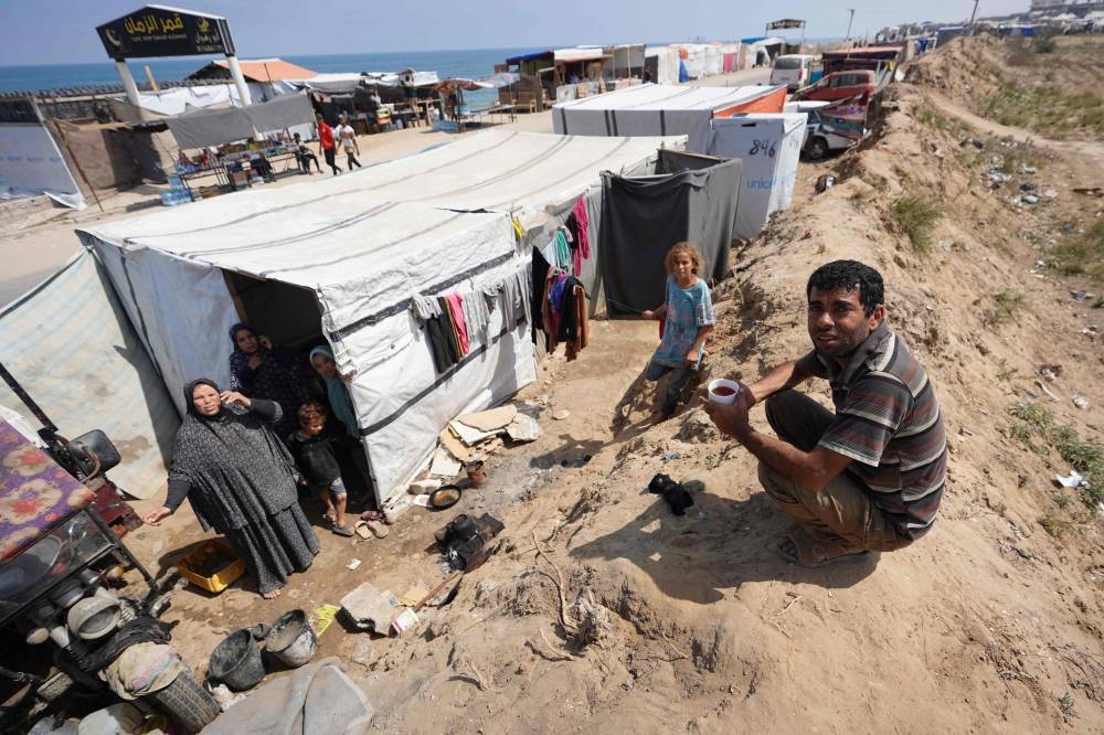 Displaced Palestinians gather outside their tents in Deir al-Balah in the central Gaza Strip on Monday. AFP