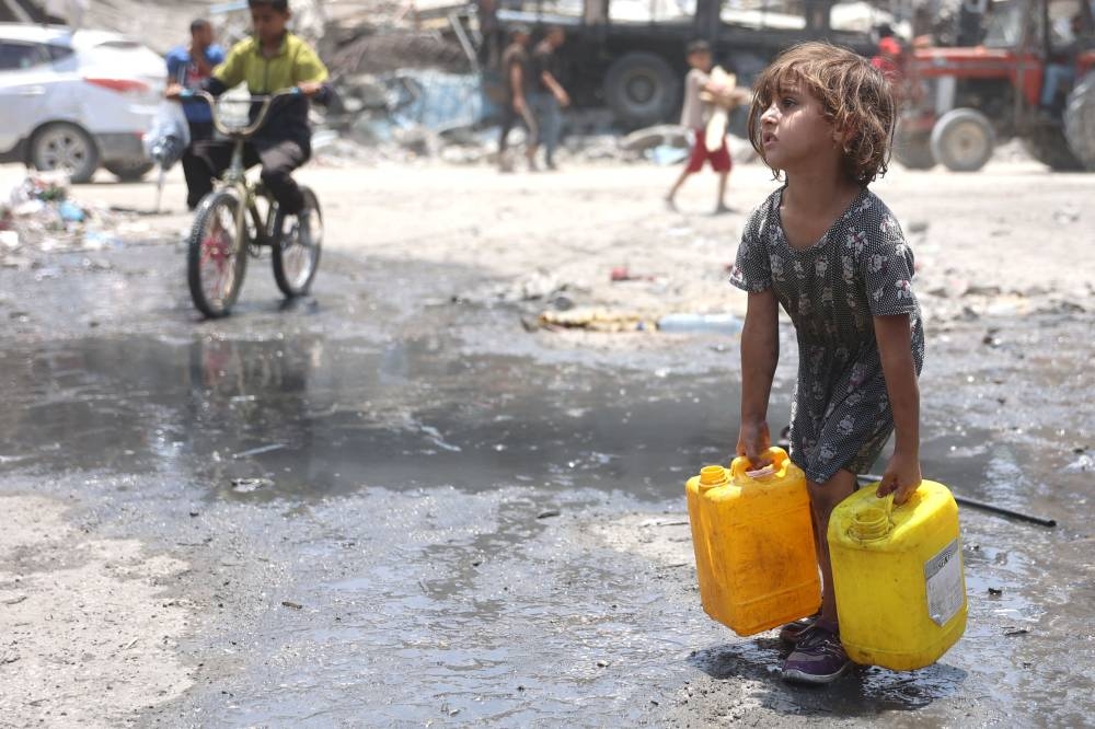 A Palestinian girl carries containers holding water in Jabalia refugee camp in the northern Gaza Strip on Monday. AFP