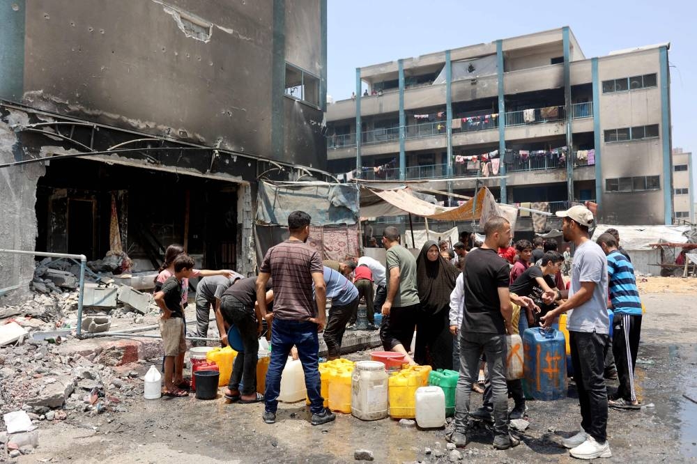 Gazans wait to fill containers with water at a standpipe in the grounds of the partially destroyed school used to shelter internally displaced Palestinians in the Jabalia refugee camp in the northern Gaza Strip on Monday. AFP