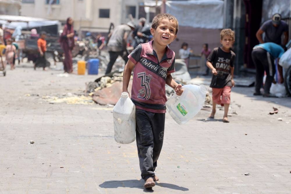 A Palestinian boy carries containers holding water in Jabalia refugee camp in the northern Gaza Strip on Monday. AFP