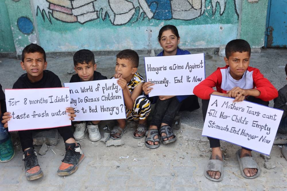 Children hold signs at a UN school housing displaced Palestinians in Gaza City on Tuesday. AFP