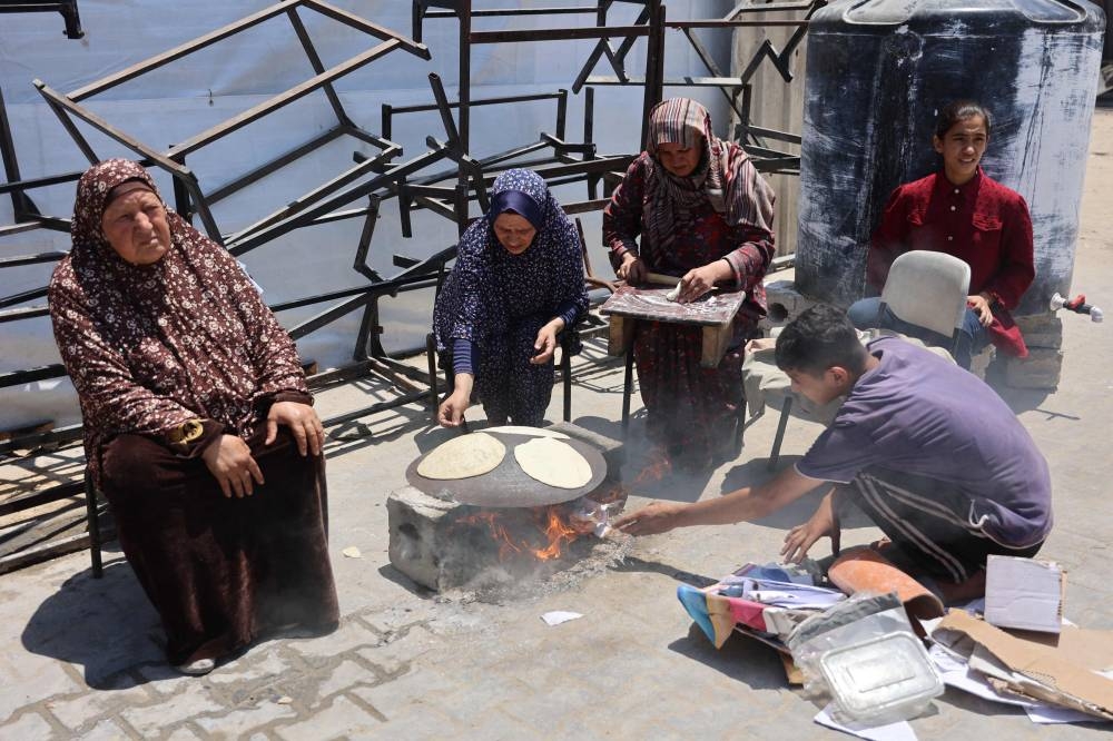 Palestinians use cardboard to light a fire to cook bread at a UN school housing displaced people in Gaza City on Tuesday. AFP