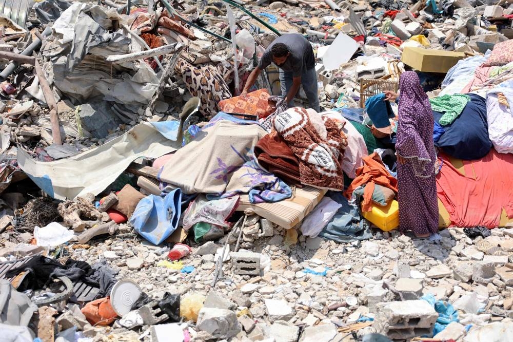A Palestinian man and woman retrieve what they can from under the rubble of destroyed buildings in the Jabalia refugee camp, in the northern Gaza Strip on Monday. AFP