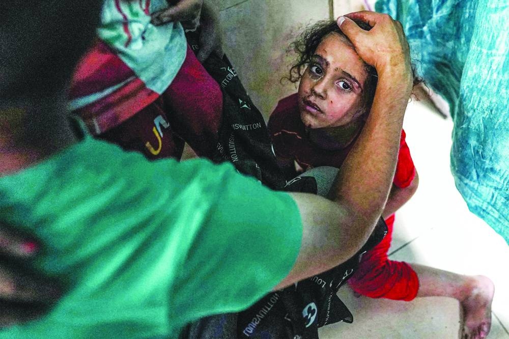 An injured child reacts as she sits on the floor at a ward at the Aqsa Martyrs hospital in Deir el-Balah in the central Gaza Strip Tuesday.