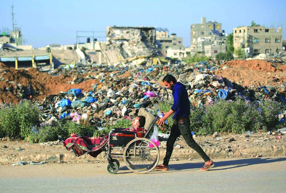 A Palestinian man pushes another on a wheelchair at al-Maghazi refugee camp in the central Gaza Strip Wednesday.