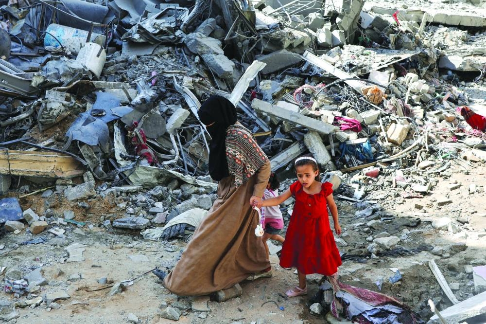 A woman and child walk among debris in Nuseirat refugee camp in the central Gaza Strip, on Sunday.