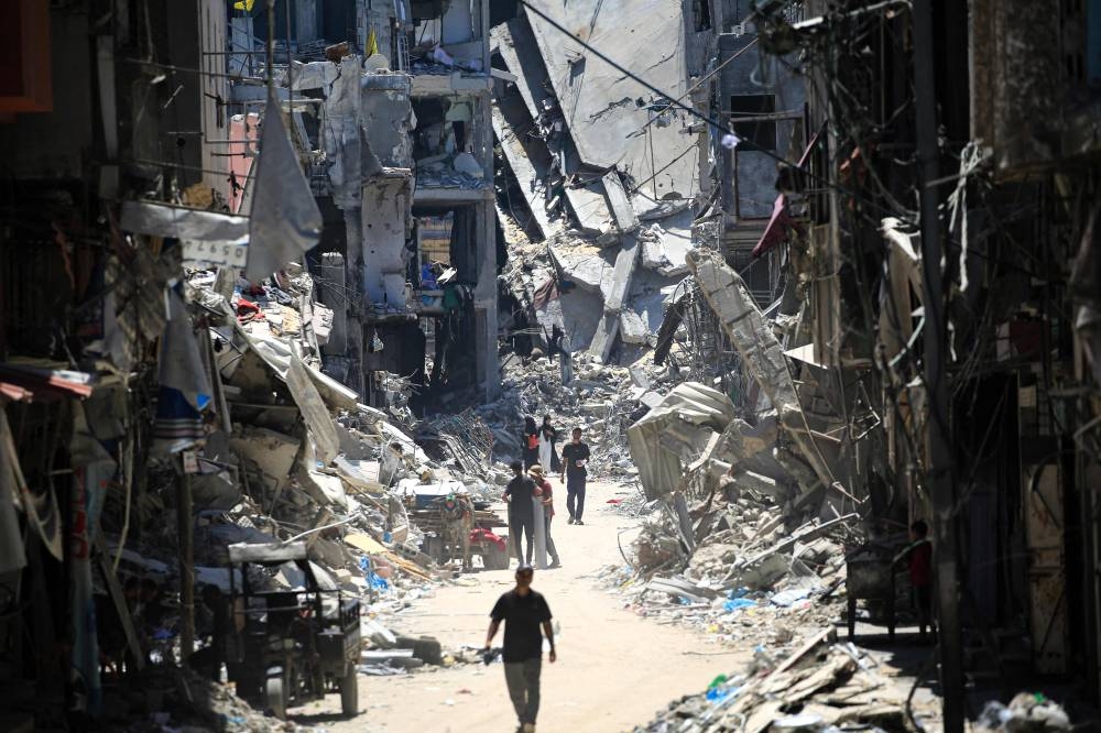 Palestinian men walk along a narrow street past destroyed buildings in Khan Yunis, in the southern Gaza Strip on Tuesday. AFP
