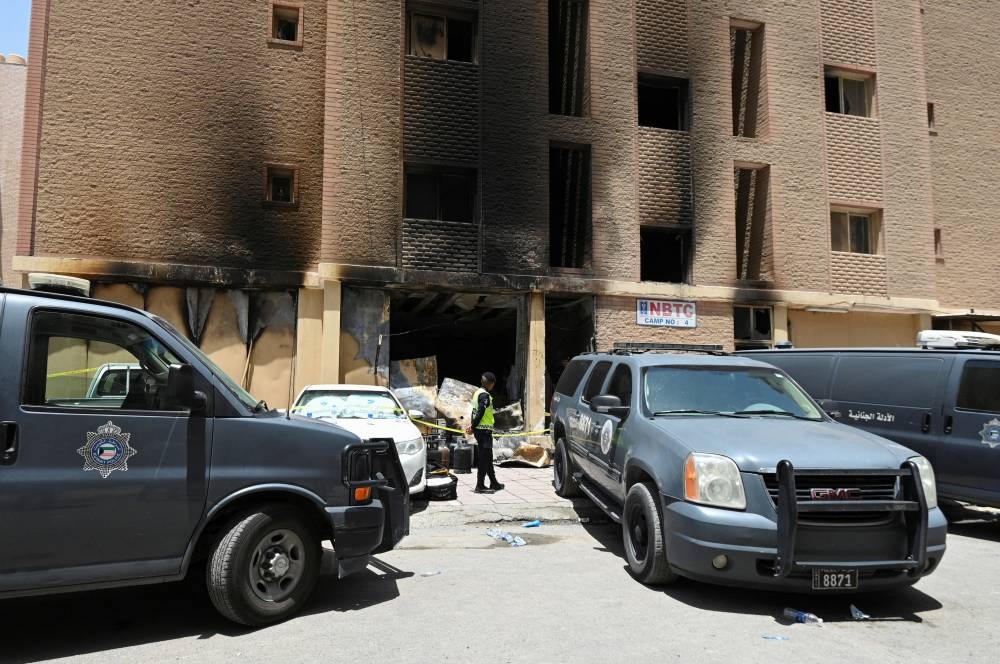 A Kuwaiti police officer is seen in front of a burnt building following a deadly fire, in Mangaf, southern Kuwait, on Wednesday. REUTERS