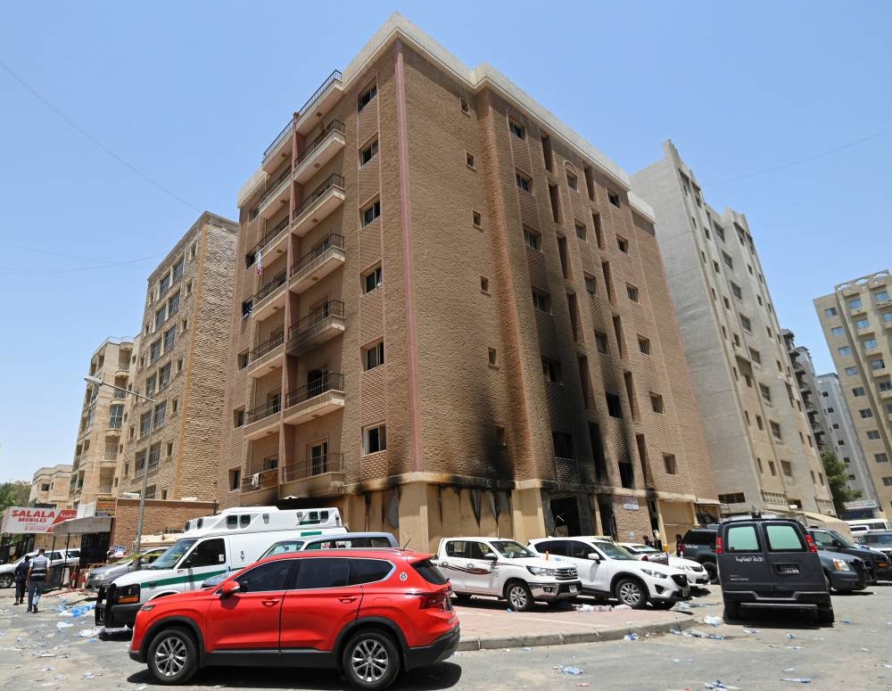 Vehicles are parked next to a building damaged following a deadly fire, in Mangaf, southern Kuwait, on Wednesday. REUTERS