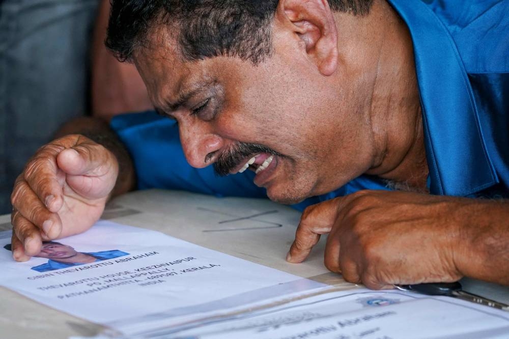 A relative mourns near deceased Cibin Abraham after his coffin arrived on an Indian Air Force plane from Kuwait at the Cochin International Airport in Kochi on Friday. AFP