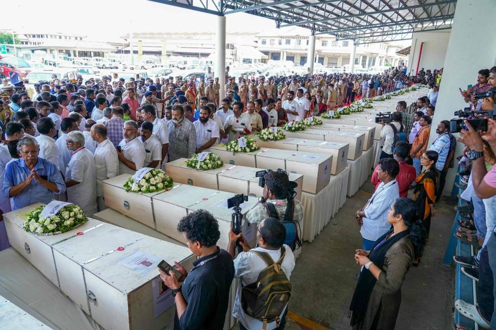 Relatives mourn near the deceased after the coffins' arrival on an Indian Air Force plane from Kuwait at the Cochin International Airport in Kochi on Friday. AFP