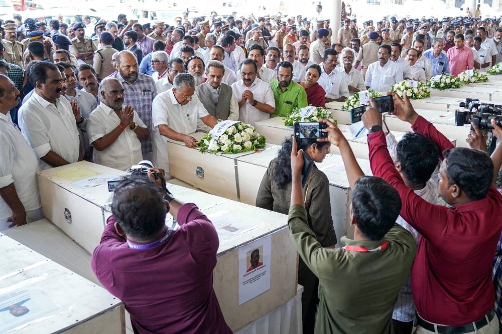 Kerala chief minister Pinarayi Vijayan lays a wreath on the deceased after coffins' arrival on an Indian Air Force plane from Kuwait at the Cochin International Airport in Kochi on Friday. AFP