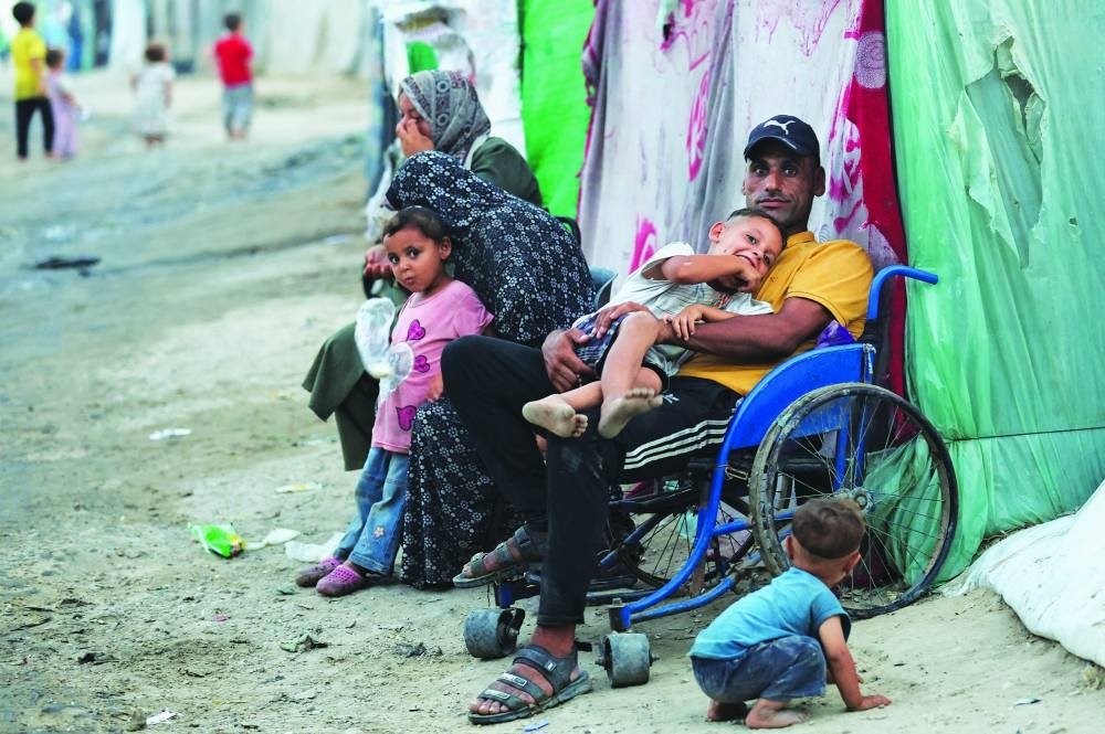 A Palestinian man holds a child as he sits on a wheelchair, ahead of Eid-al-Adha, in central Gaza Strip Saturday
