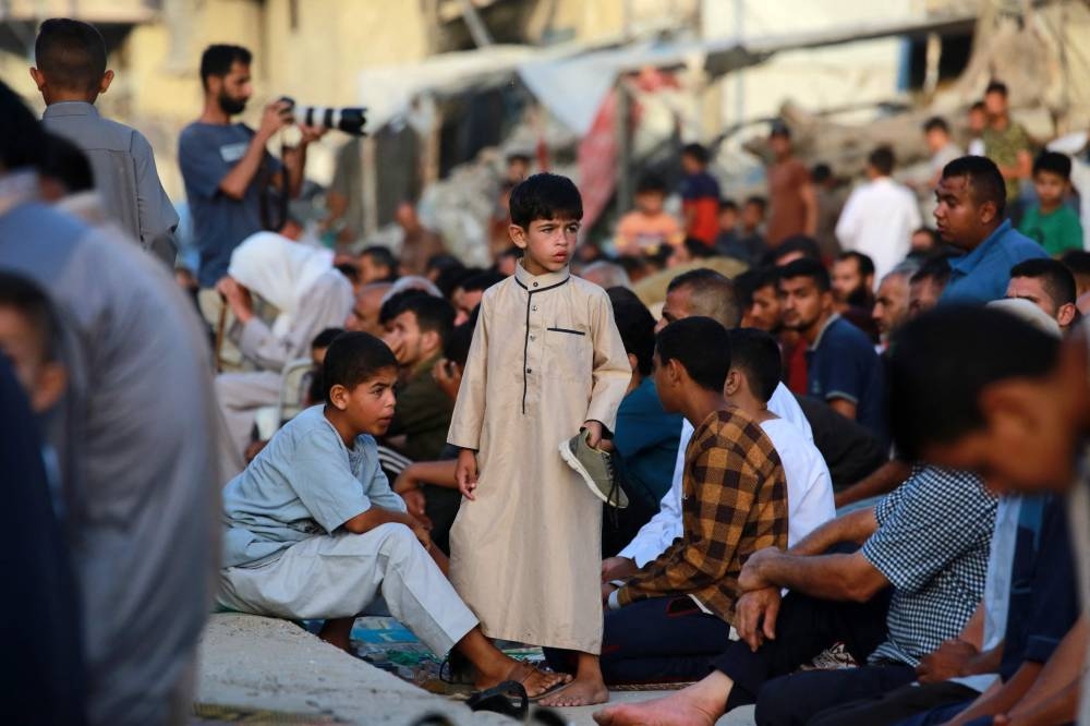 A young boy stands amid Palestinians performing the Eid al-Adha morning prayer in Khan Yunis in the southern Gaza Strip ,on Sunday. AFP