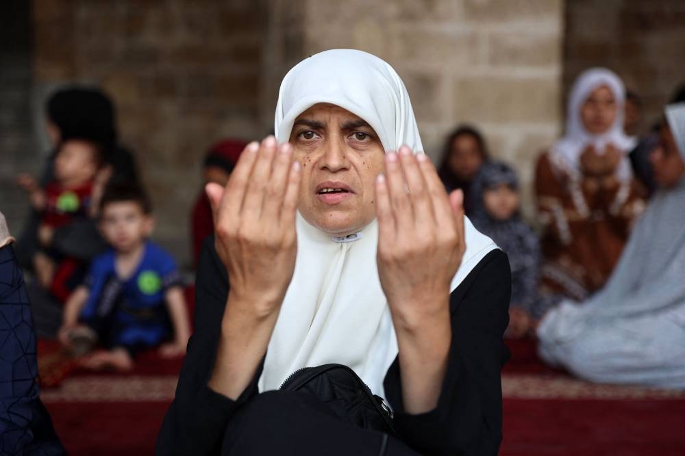 A Palestinian woman performs the Eid al-Adha morning prayer in the courtyard of Gaza City's historic Omari Mosque, which was heavily damaged in Israeli bombardment during the ongoing battles between Israel and Hama. AFP