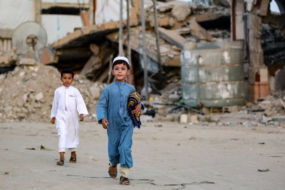 A Palestinian boy carrying his prayer mat, walks to join the morning the Eid al-Adha prayer in Khan Yunis in the southern Gaza Strip, on Sunday. AFP