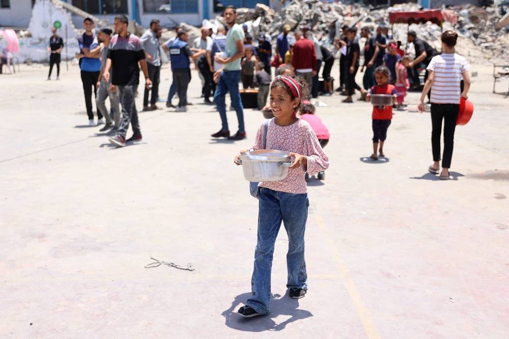A child carries food at a UN Relief and Works Agency for Palestine Refugees (UNRWA) school in the Jabalia camp for Palestinian refugees in the northern Gaza Strip, on Monday. AFP