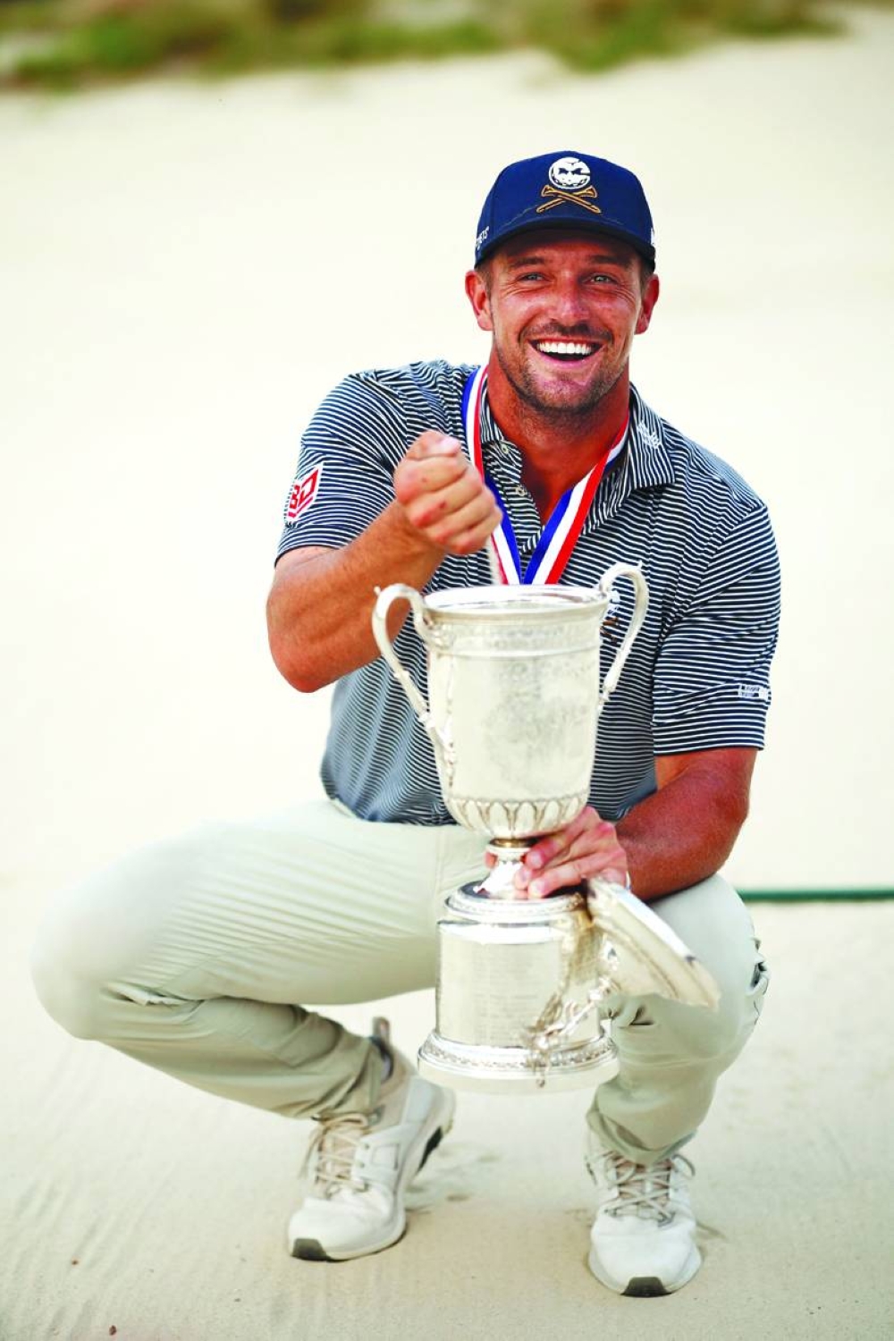 
Bryson DeChambeau pours sand from a bunker into the US Open trophy, after his superb up-and-down approach shot secured the title. (AFP) 