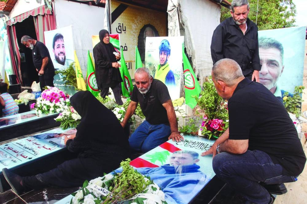 Relatives visit the graves of killed Hezbollah fighters during Eid al-Adha, in the southern Lebanese town of Naqura near the border with Israel, on Monday.