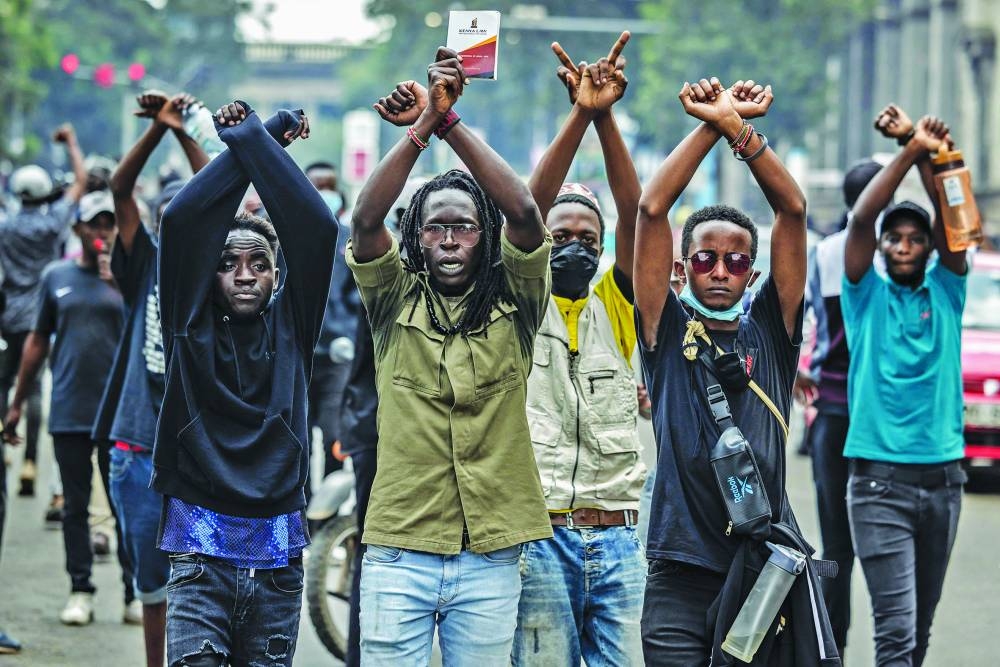 
Protesters make signs with their arms in front of Kenya police officers. 