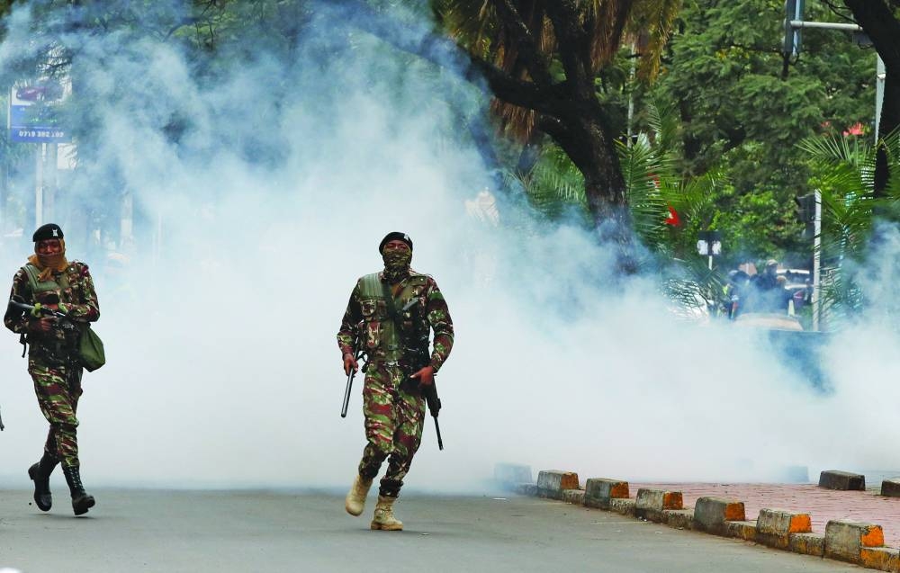 
Police officers run after using teargas to disperse protesters. 