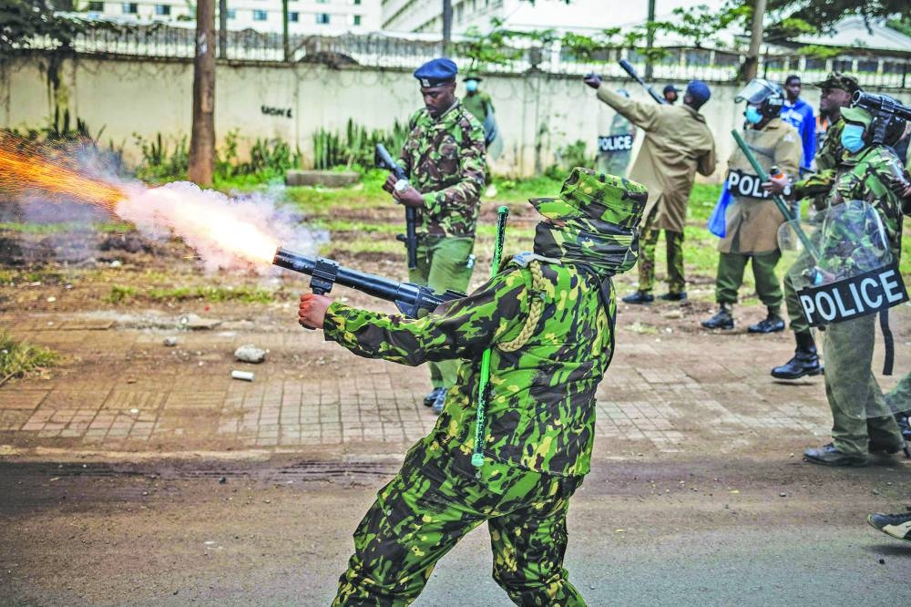 
A Kenya police officer fires a tear gas canister. 