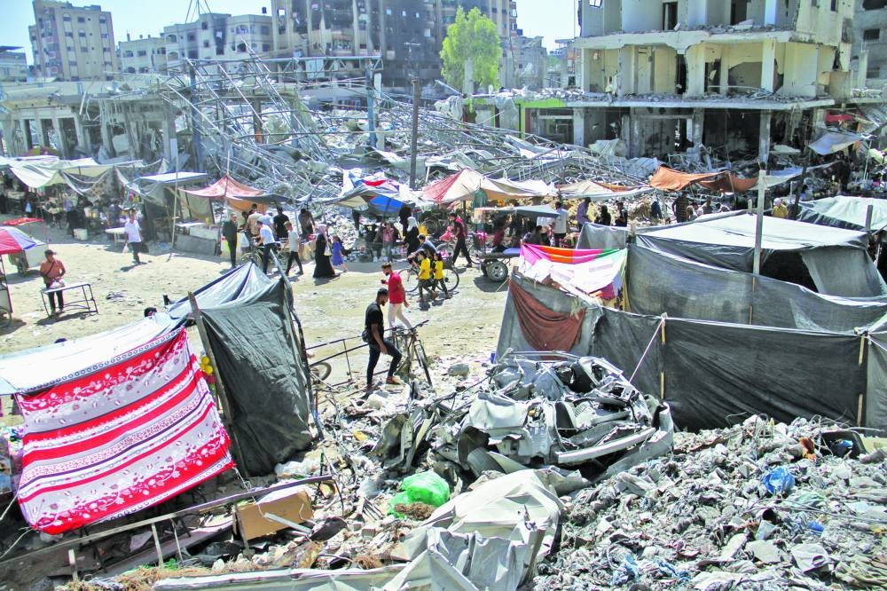 Palestinians walk near destroyed houses, in Jabalia refugee camp, in the northern Gaza Strip
