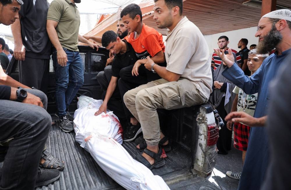 A child reacts in front of the body as people gather to mourn Palestinians killed in Israeli strikes in Gaza City, on Friday. REUTERS