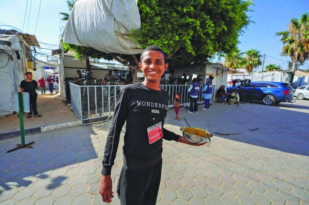 
A Palestinian youth poses for a picture with a food ration he managed to get from a distribution spot in Deir Al-Balah in the central Gaza Strip, yesterday, amid the ongoing conflict between Israel and the Palestinian Hamas movement. 