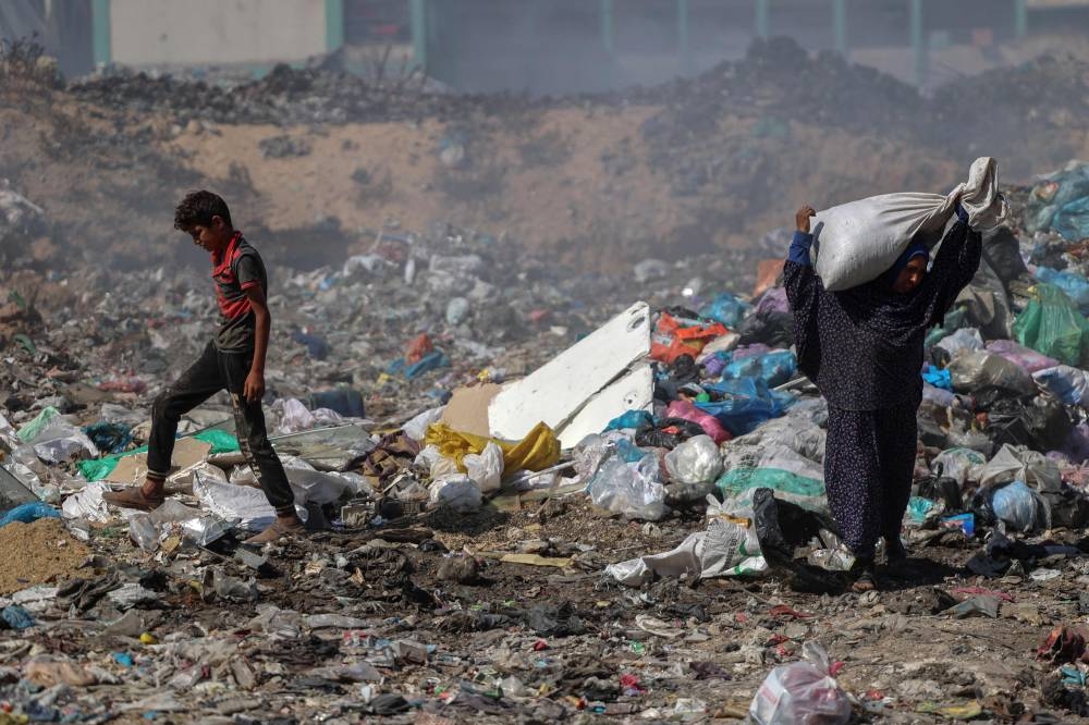 Palestinians search for salvageable items in a garbage dump which sprawls across what used to be the Firas market in Gaza City on Monday. AFP