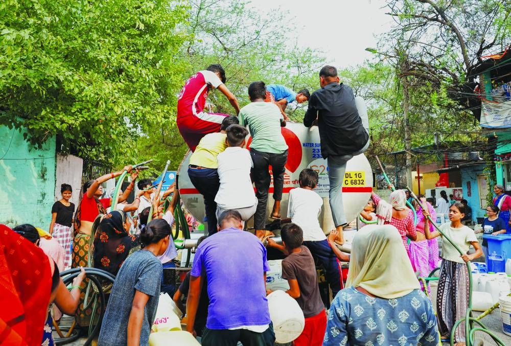 People rush to climb a water tanker as it arrives to deliver drinking water during the ongoing water crisis in New Delhi, India, yesterday.
