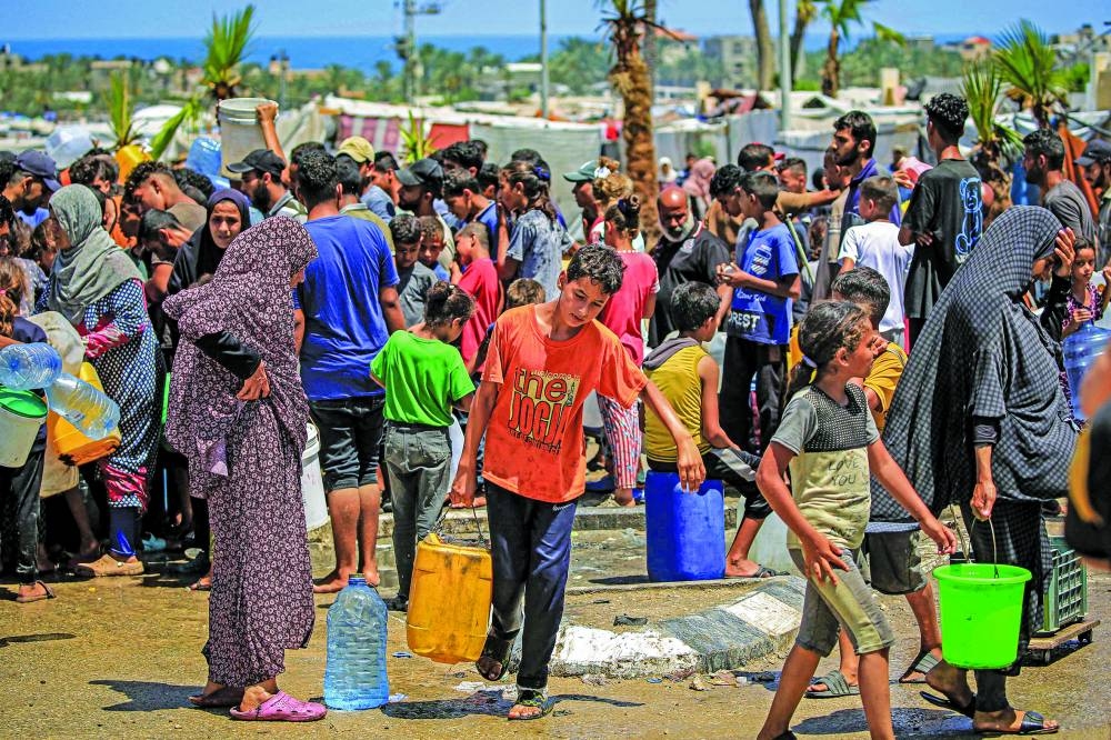 A boy walks with a jerrycan after filling up with others from a truck loaded with water cisterns in Rafah in the southern Gaza Strip, yesterday, amid the ongoing conflict in the Palestinian territory between Israel and Hamas. 