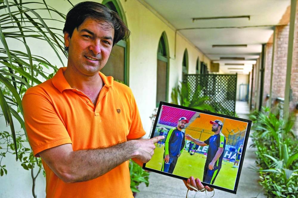 Ali Hoti, sports teacher of Afghanistan’s national cricket team captain Rashid Khan, shows a framed photograph of Khan during an interview at Islamia cricket club in Peshawar, Pakistan, on Wednesday. (AFP)