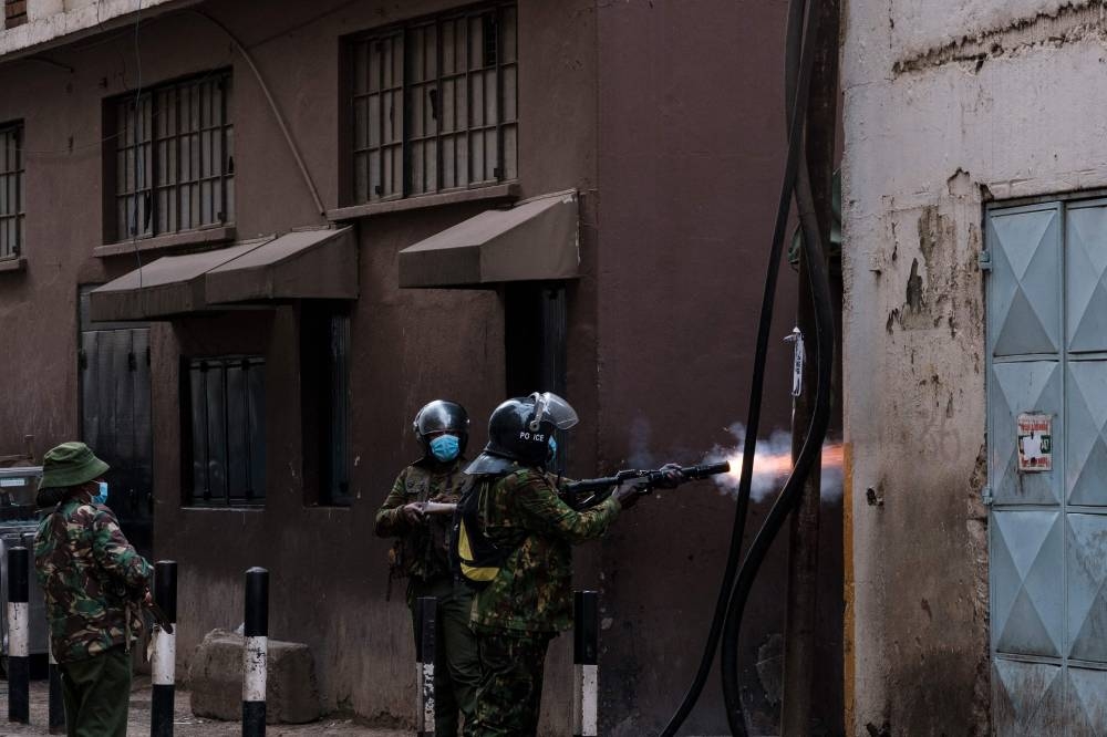 A Kenyan policeman fires a stun grenade at protestors at a planned demonstration called after a nationwide deadly protest against a controversial now-withdrawn tax bill left over 20 dead in downtown Nairobi, on June 27, 2024. Kenyans are preparing to take to the streets on Thursday for a white march the day after President William Ruto announced the withdrawal of the draft budget providing for tax increases, at the origin of a protest which foundered in murderous violence. (Photo by Kabir Dhanji / AFP)