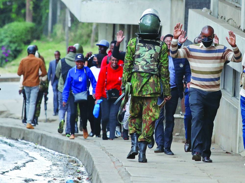 
People lift their hands as they walk near a police officer during a demonstration over police killings of people protesting against Kenya’s proposed finance bill 2024/2025, in Nairobi, yesterday. 