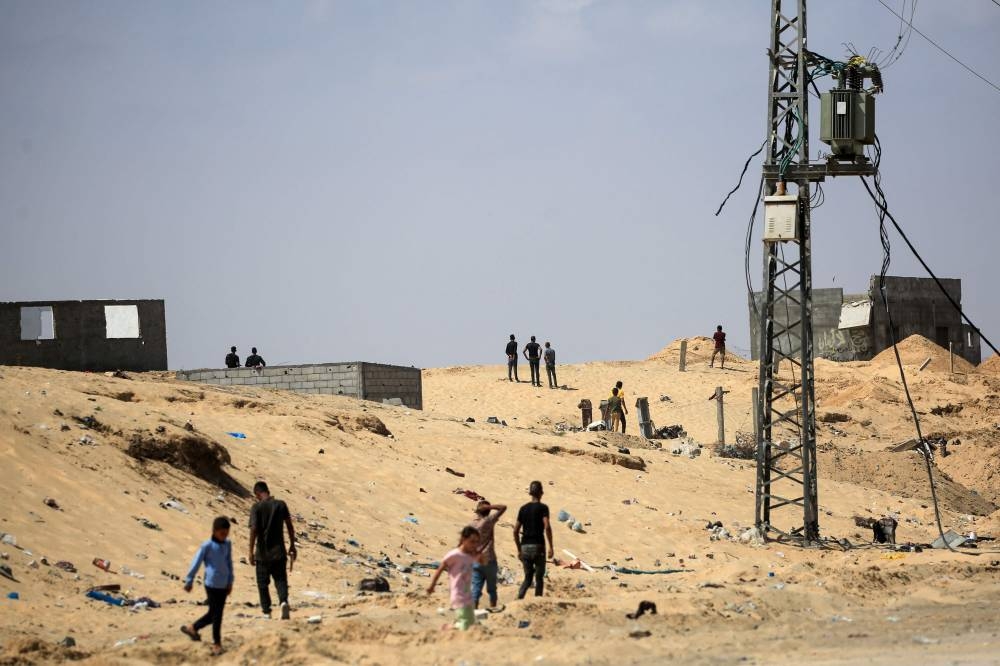 Palestinians stand next to damaged buildings in Rafah, on the southern Gaza Strip on Saturday. AFP