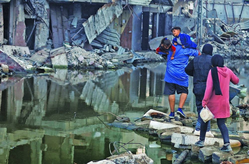 A man holds his children as he walks next to buildings destroyed in an Israeli strike in Khan Younis, in the southern Gaza Strip, Sunday.