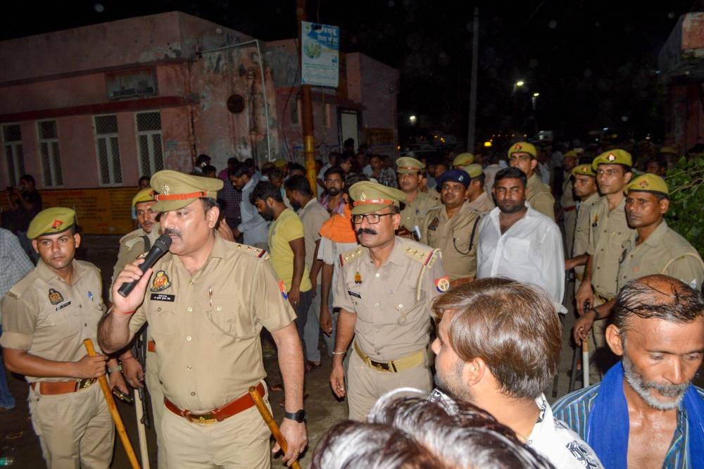 Policemen manage the mourners as the deceased who died in a melee during a sermon, are brought to a hospital in Hathras, Tuesday. AFP