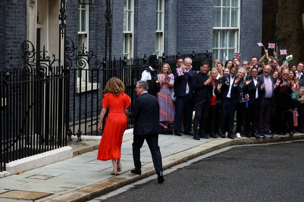 British Prime Minister Keir Starmer and his wife Victoria Starmer hold hands as they walk next to supporters outside Downing Street 10, following the results of the election, in London, Friday. REUTERS