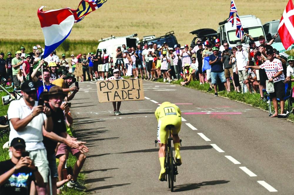 A young spectator holding a placard faces down UAE Team Emirates’ Slovenian rider Tadej Pogacar wearing the overall leader’s yellow jersey as he cycles during the 7th stage of the 111th edition of the Tour de France cycling race, 25.3km individual time trial between Nuits-Saint-Georges and Gevrey-Chambertin, on Friday. (AFP)