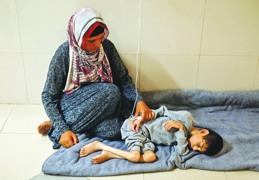 Palestinian mother Ghaneyma Joma sits next to her malnourished son Younis Joma, at Nasser hospital in Khan Younis, in the southern Gaza Strip, Monday.
