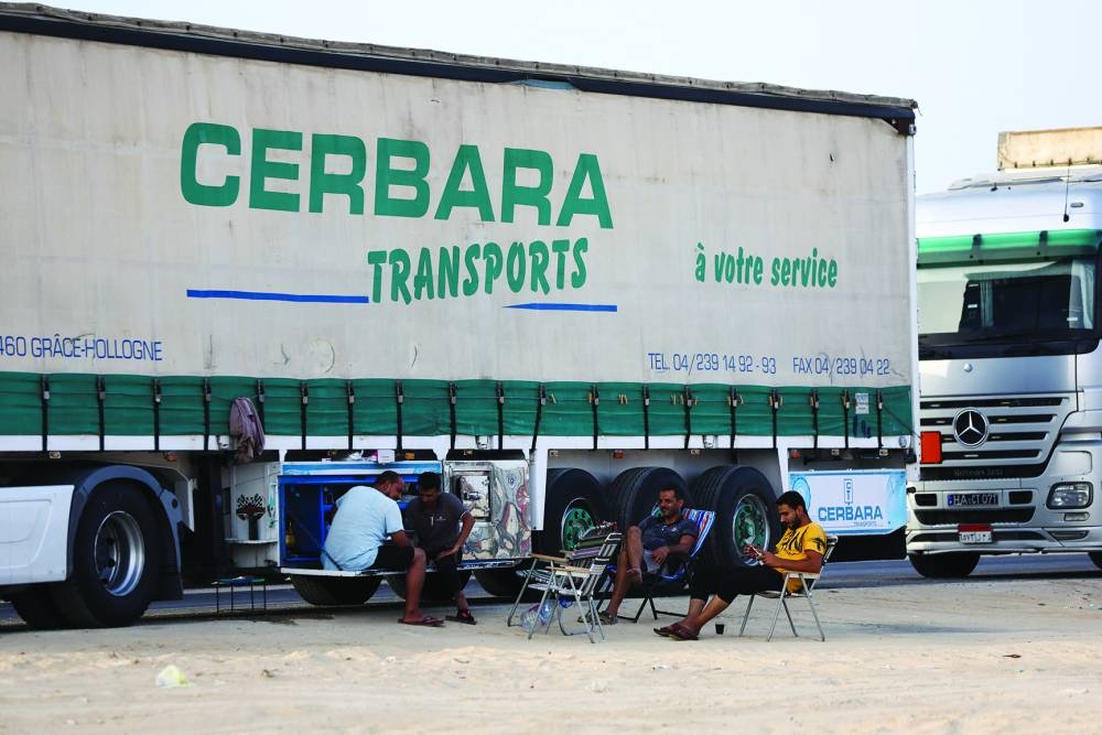 Truck drivers sit near lines of aid trucks for Gaza waiting to be deployed, in Al-Arish, Egypt.