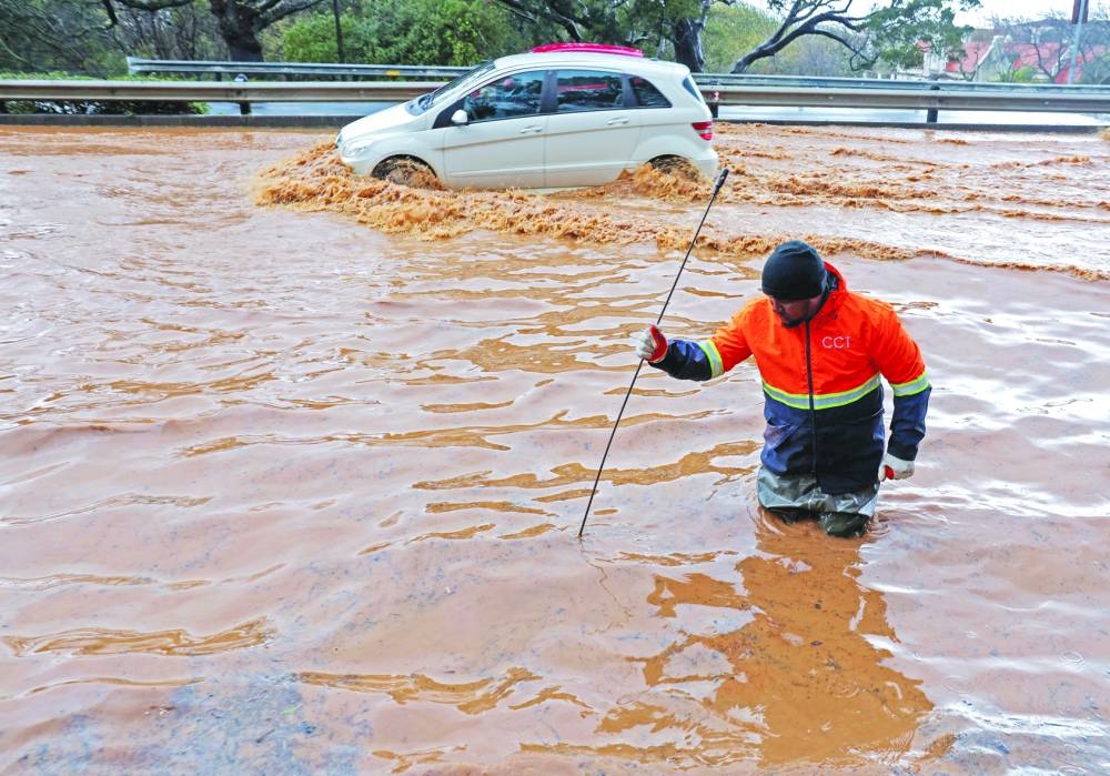 A municipal worker attempts to unclog a flooded road in Newlands during heavy rains in Cape Town, South Africa, yesterday.
