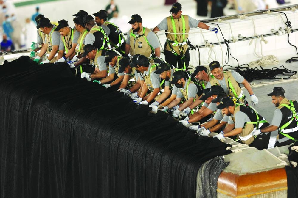 Saudi workers adjust the new Kiswa cover that adorns the Holy Ka'aba.