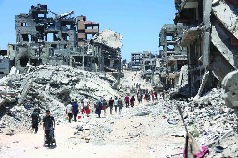 
Palestinians walk past destroyed buildings after the Israeli military withdrew following a two-week offensive in the Shujaiya neighbourhood, east of Gaza City, yesterday. 