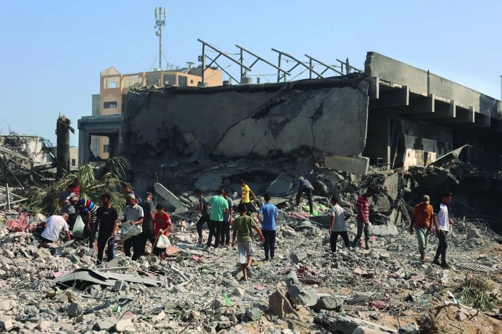 People walk on rubble as they inspect the damage at the UN Relief and Works Agency for Palestine Refugees (UNRWA) building complex in western Gaza City's Al-Sinaa neighbourhood, yesterday.