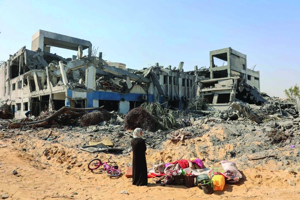 A woman looks around as she salvages items at the damaged UN Relief and Works Agency for Palestine Refugees (UNRWA) building complex in western Gaza City's Al-Sinaa neighbourhood yesterday, following the withdrawal of Israeli troops from the area.